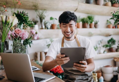 Asian male florist looking at tablet in flower shop
