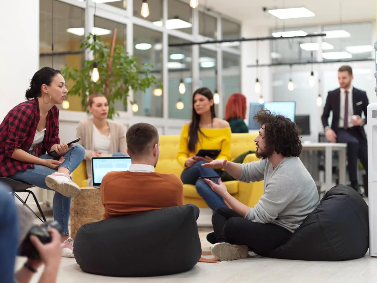 Group of young professionals sitting on floor of office discussing clients