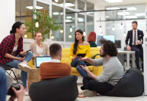 Group of young professionals sitting on floor of office discussing clients