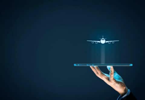 Hand holding tablet with airplane floating above aviation marketing