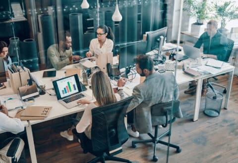 Top view of young modern people in smart casual wear communicating and using modern technologies while working in the office